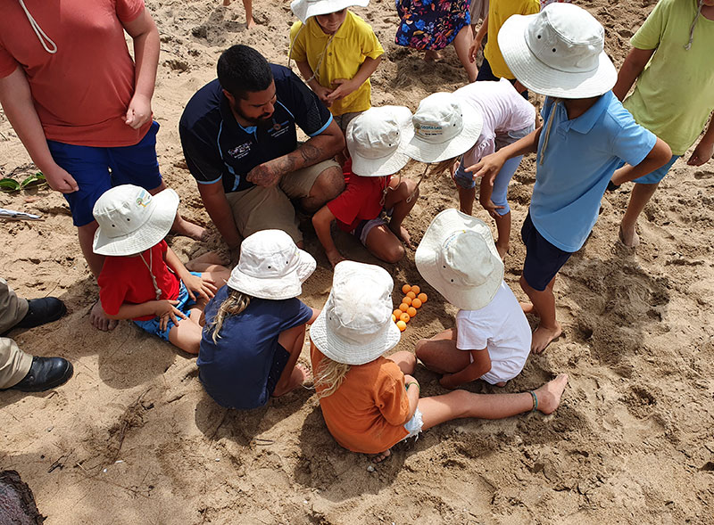 Photo of group of young students digging in the sand.