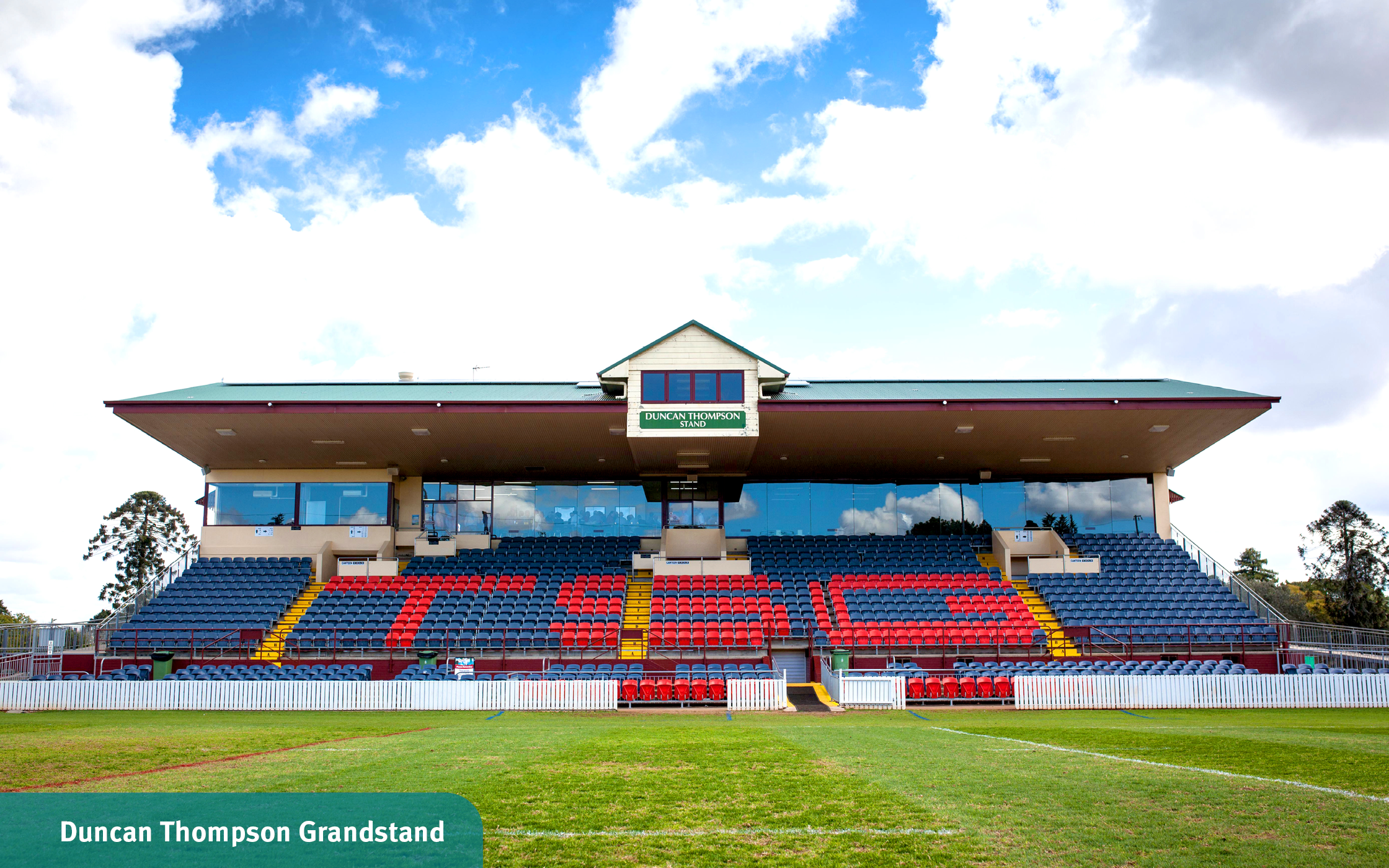 Open sky and grassy sporting field in front of the Duncan Thompson grandstand seating at Toowoomba Sports Grounds.