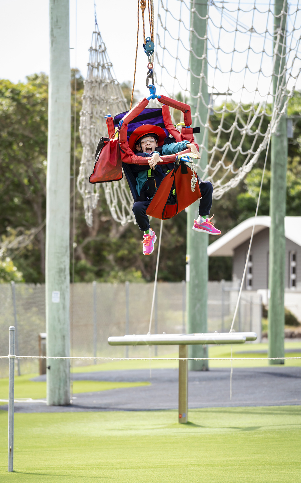Child sitting in a swing at an outdoor rope course.