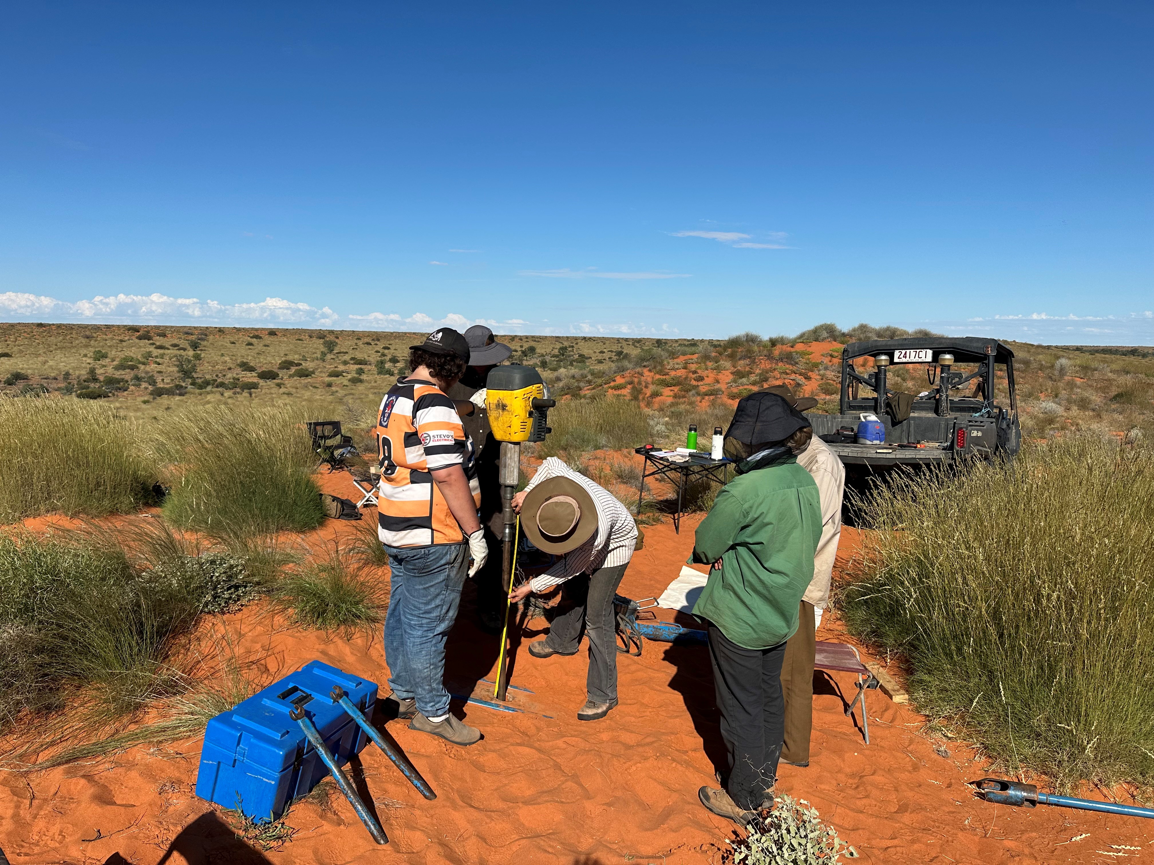 Rangers in red dirt spinifex country with research equipment
