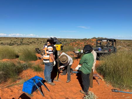 Rangers in red dirt spinifex country with research equipment