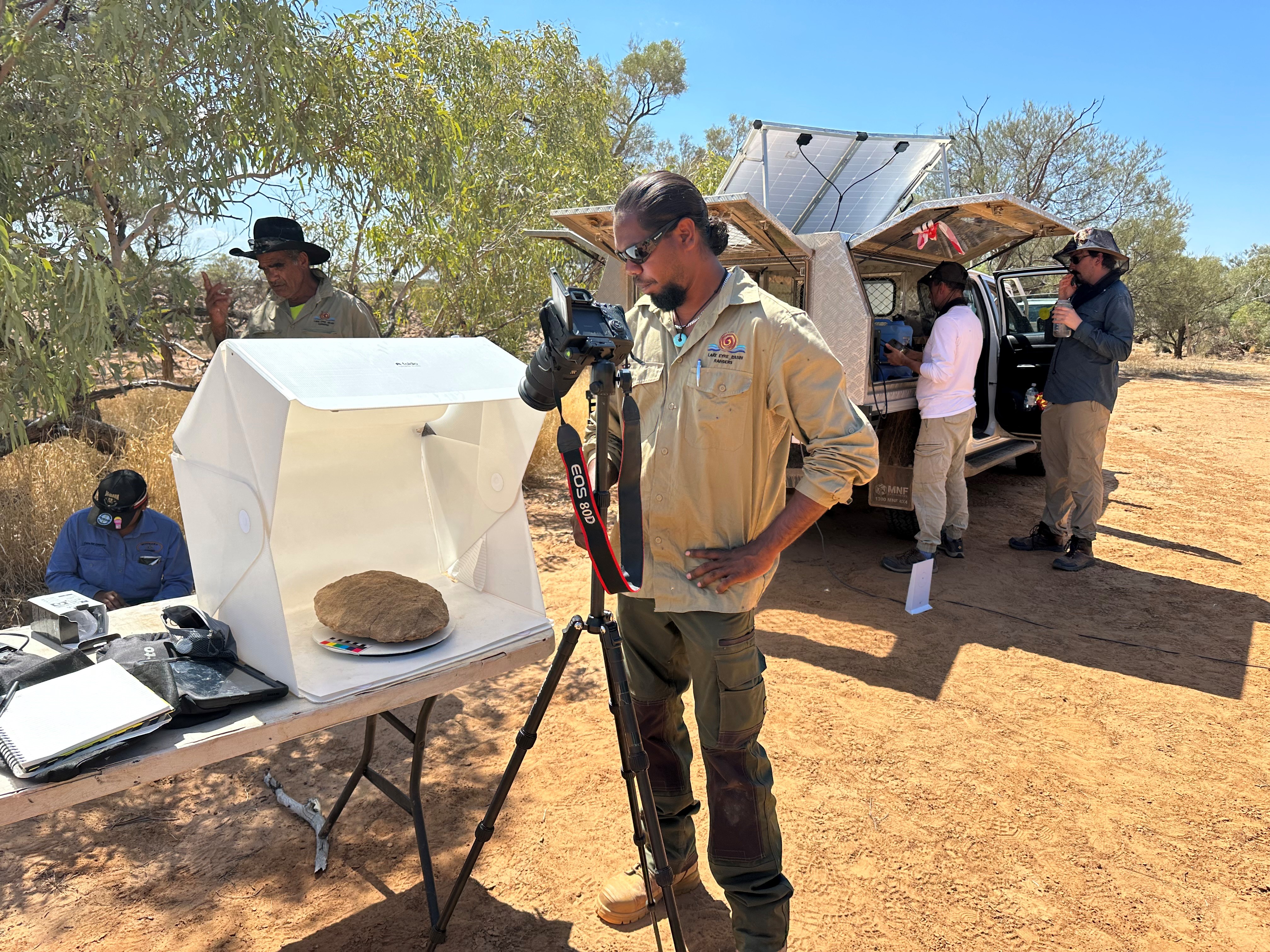 Rangers working with field equipment under shady trees