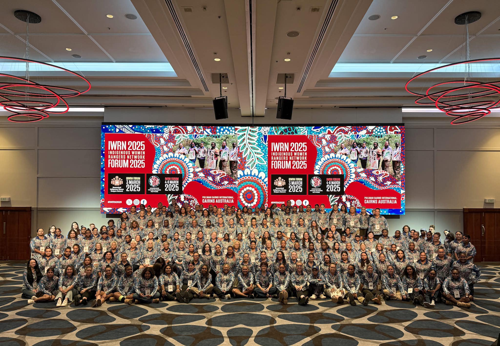 Large group of women rangers pose in front of conference banner