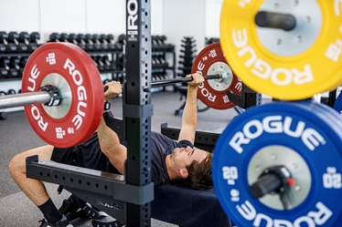Man lying on a bench pressing a weight above his chest