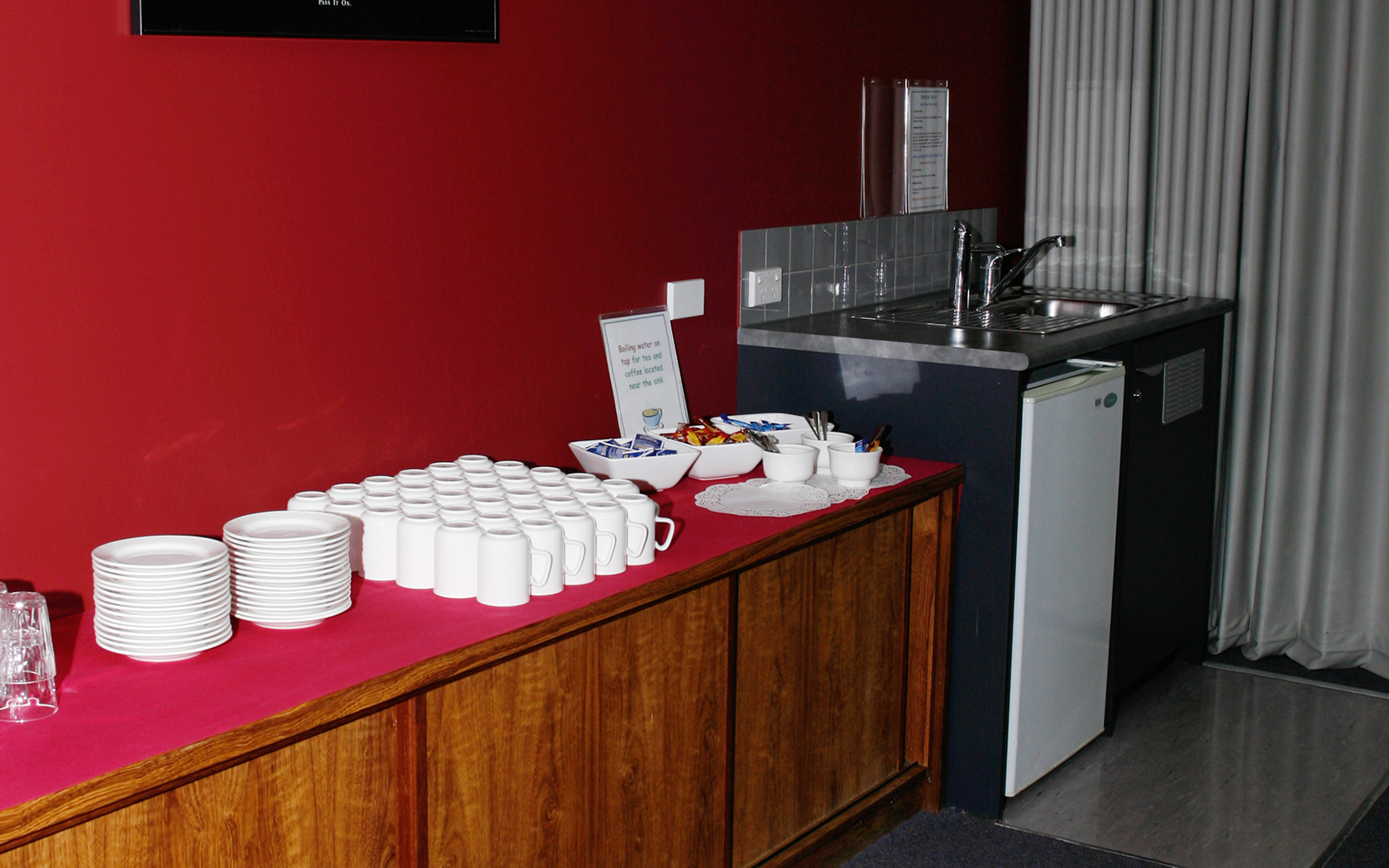 Room with tea and coffee making facilities cups and kitchenette with a mini fridge.