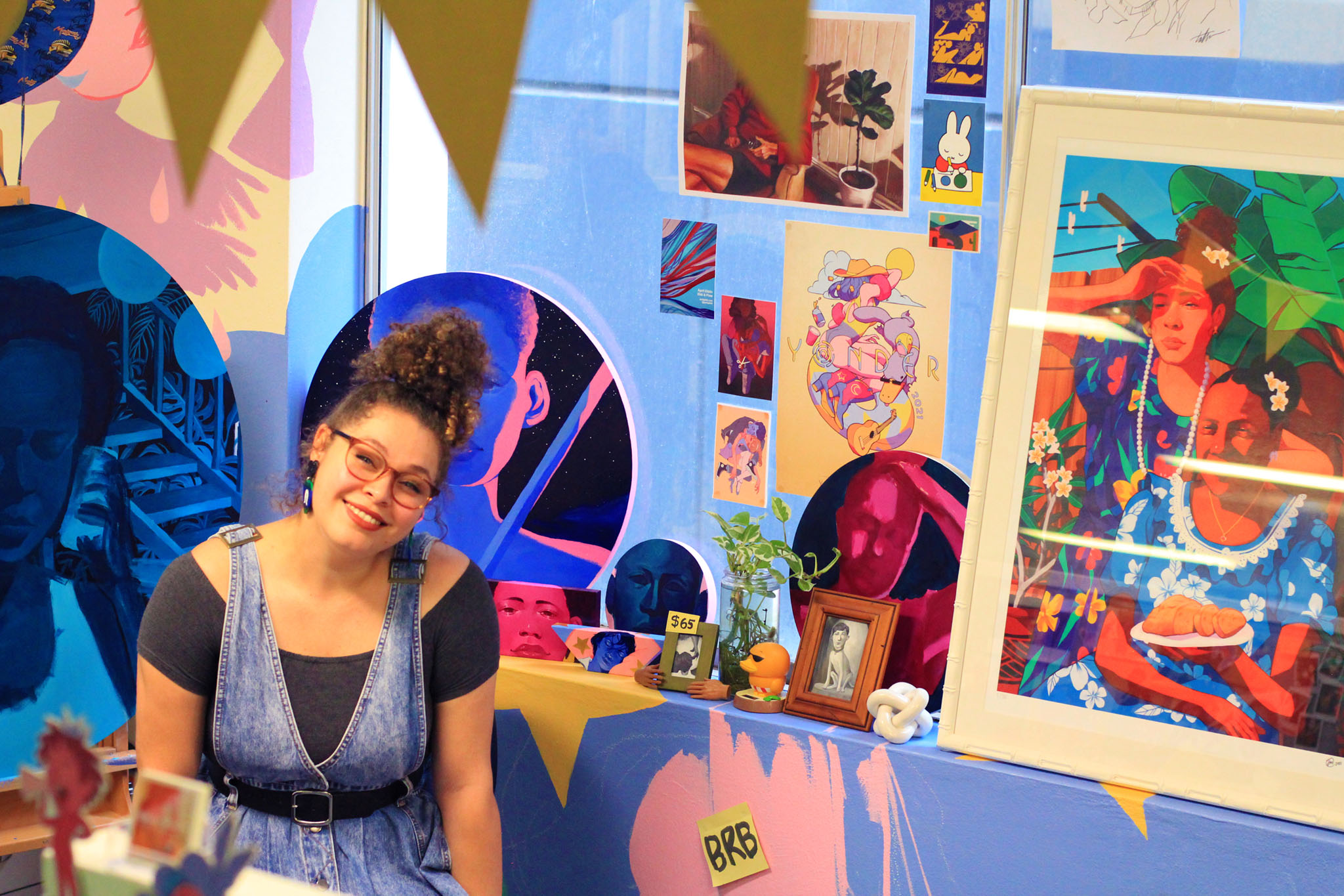 Tori-Jay sits among a stand containing examples of her artwork