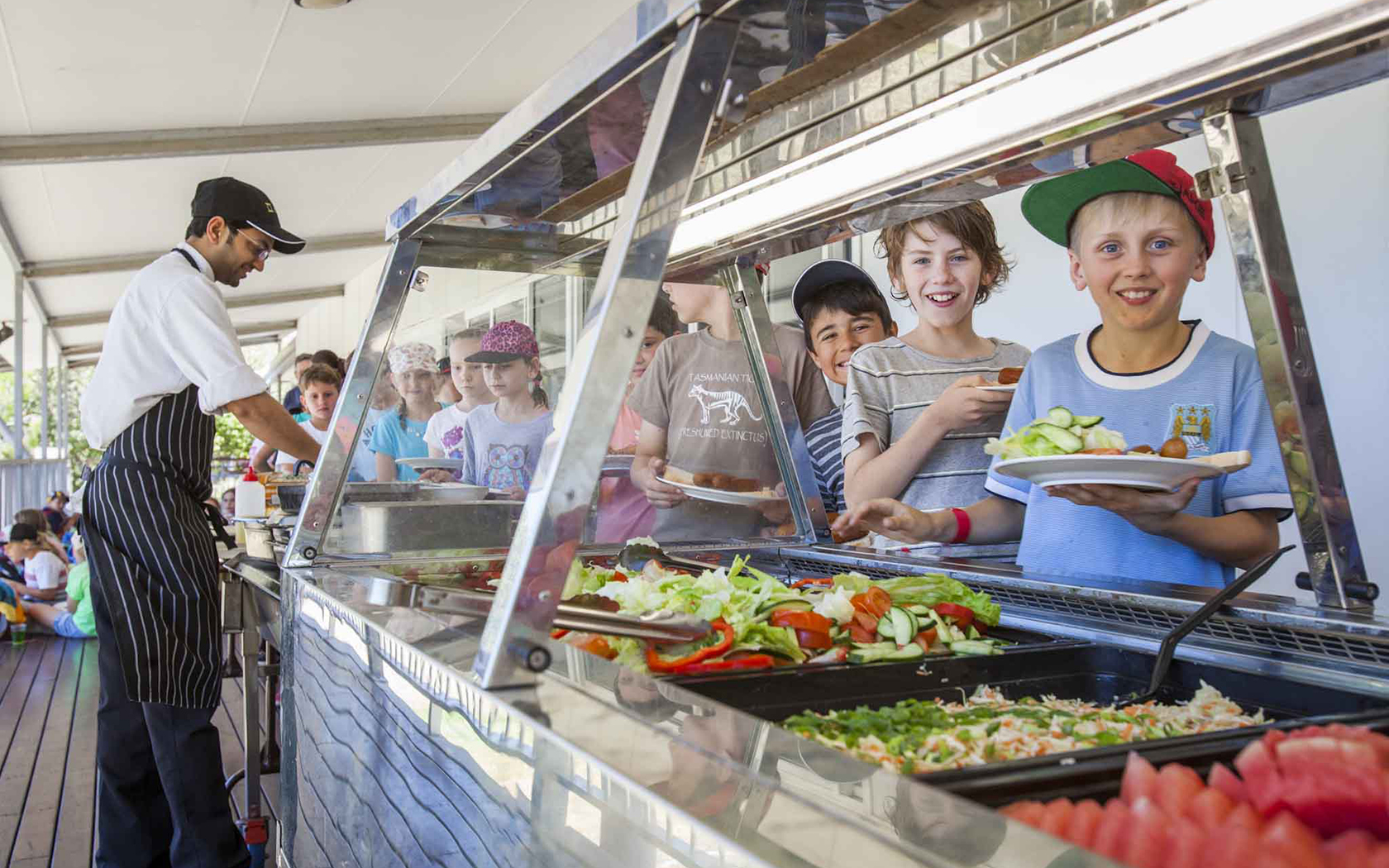 A group of children lining up at a buffet being served.