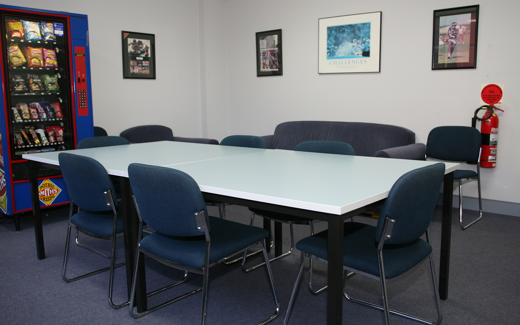 Meeting room with table, chairs and a vending machine.