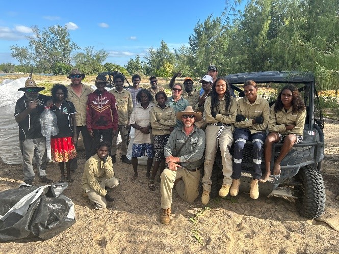 Groups of rangers and students on beach and sitting in an ATV.