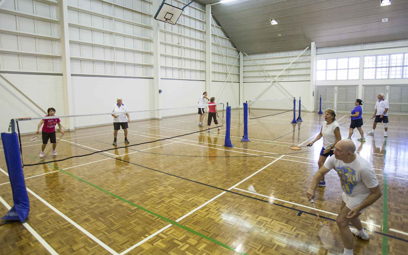 Indoor courts with nets and people ball and racquet aying