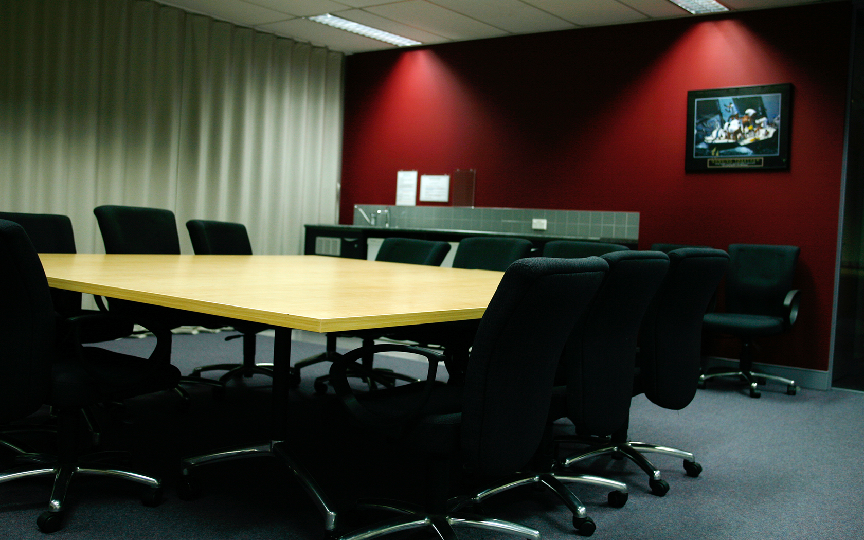 Internal meeting room with down lights, screen, table and chairs.