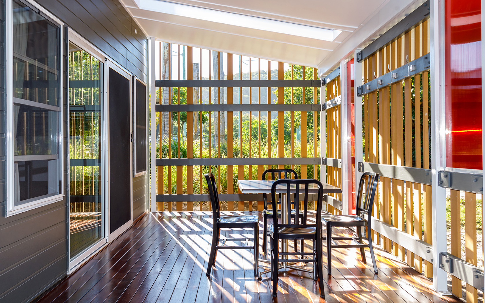 A table and chairs on a wooden deck outside a building.