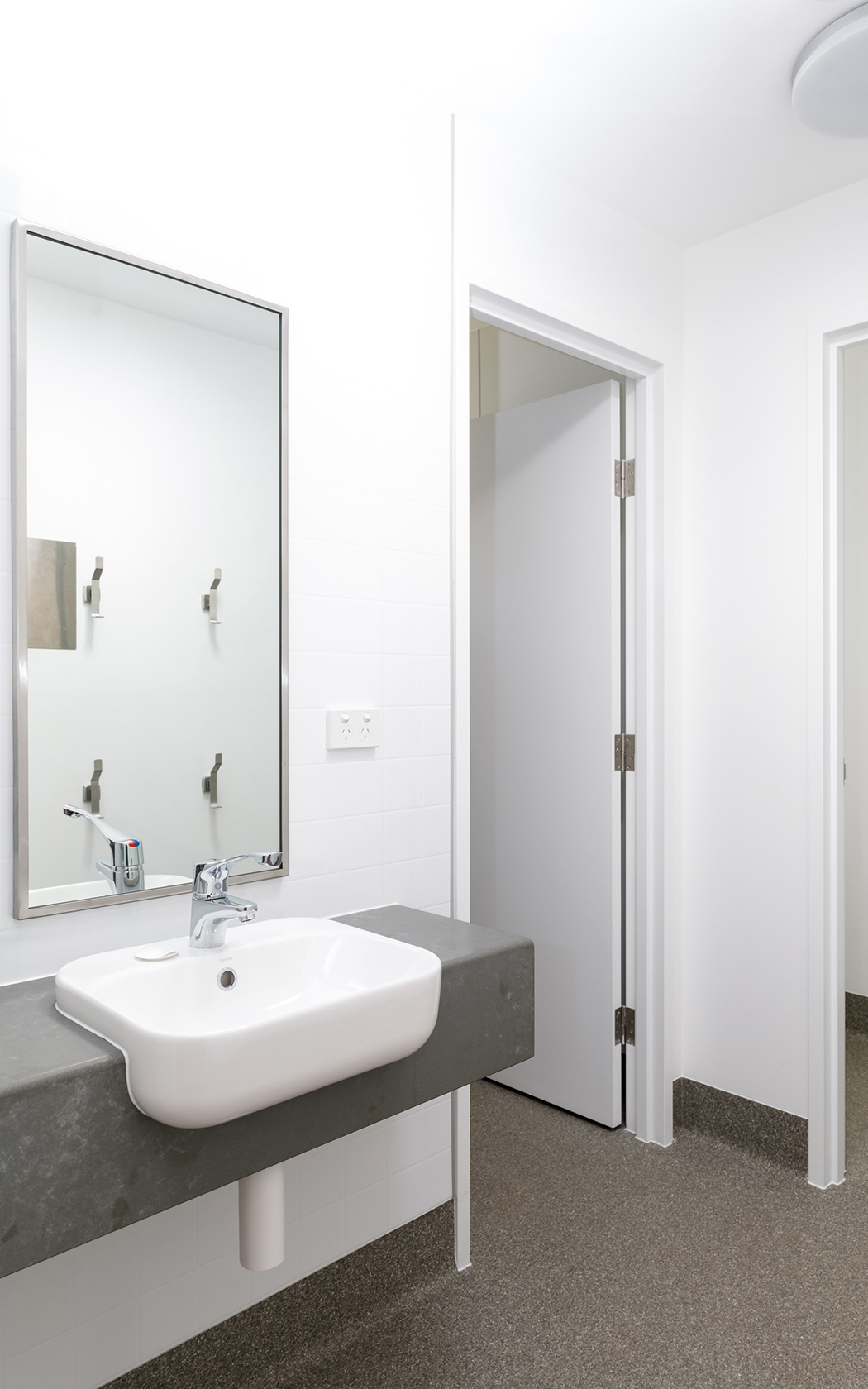 A bathroom sink with a mirror above and an open doorway.
