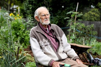old man sitting in a chair in his garden