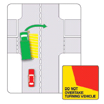A red car is behind a green truck in the traffic. The yellow areas show the space needed for the truck to turn indicating that it\'s not safe to overtake the turning truck.