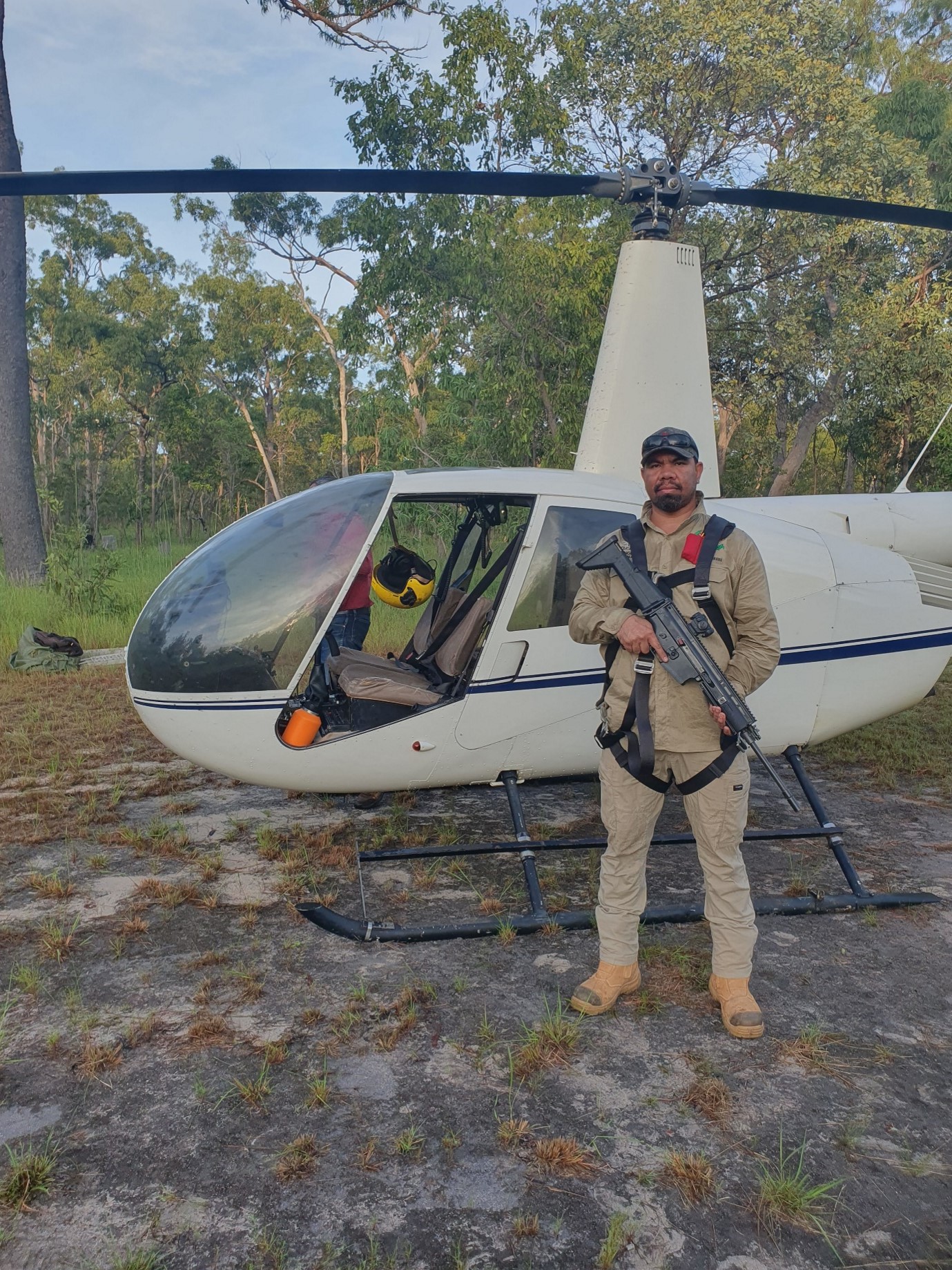 Ranger with firearm stands in front of helicopter