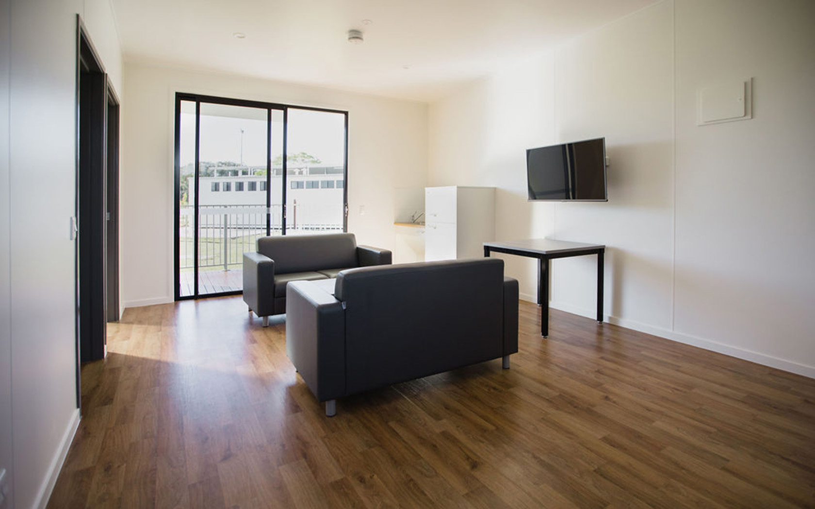 Interior view of a Shellys room showing lounges, table, tv and kitchenette.