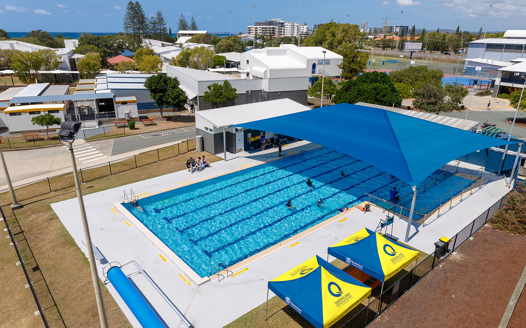 Aerial view of the pool with a half shade over the pool and people swimming